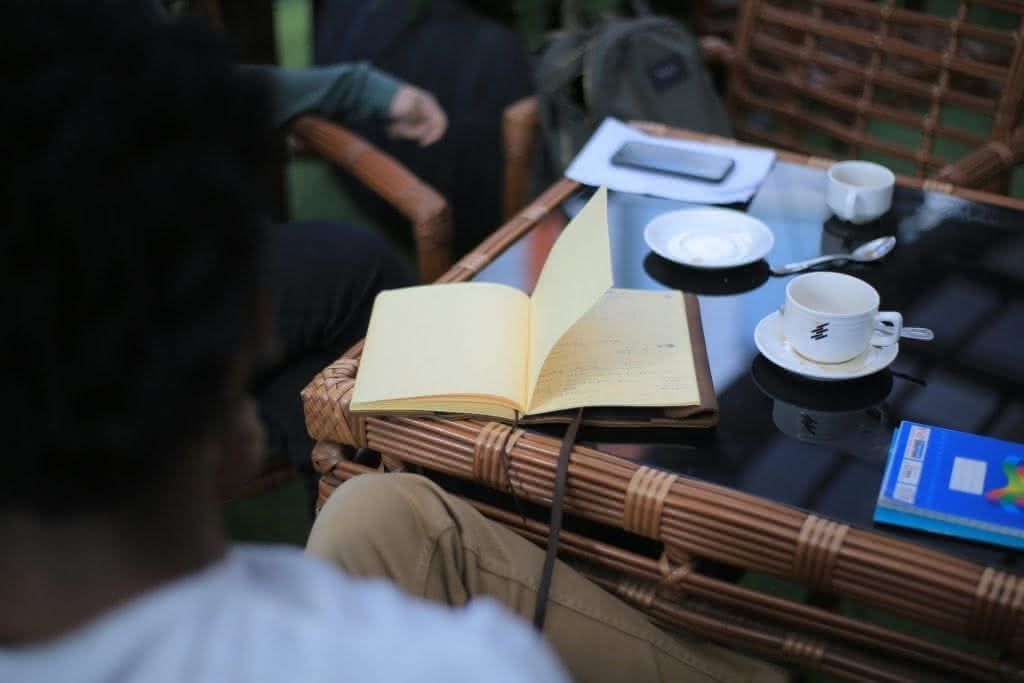 Aufgeschlagenes Notizbuch und Kaffeetassen auf einem Café-Tisch
