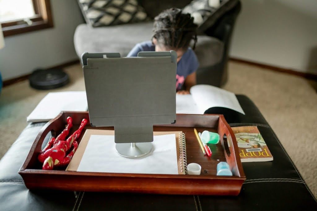 Kind lernt zu Hause mit Tablet und Schulmaterialien